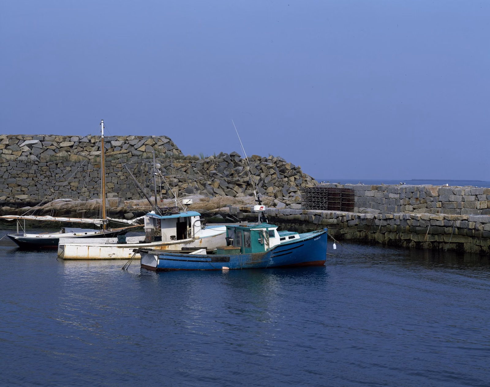 Fishing boats in the small harbor at Pigeon Cove, Rockport, behind a cut-granite seawall