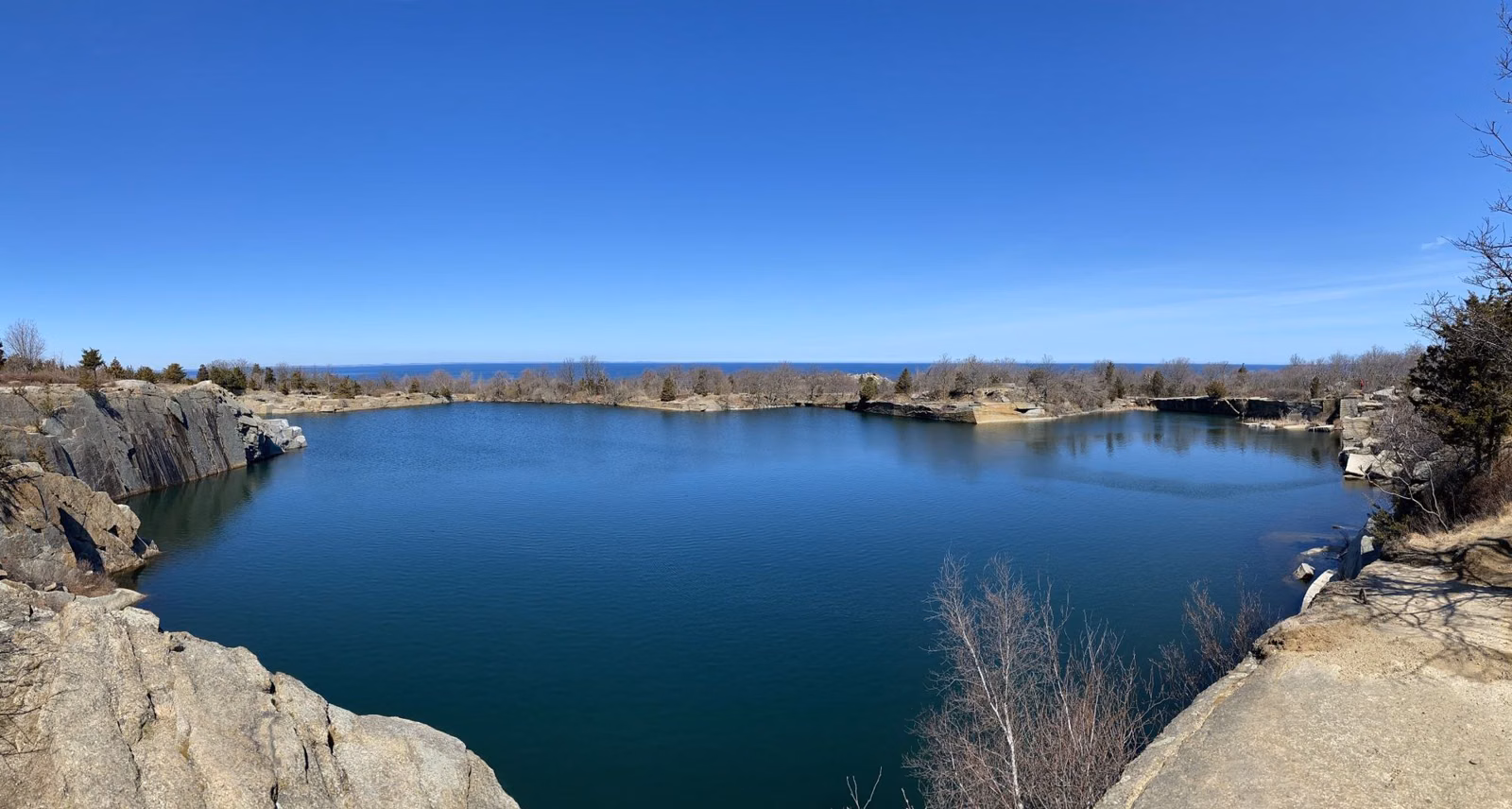 The flooded Babson Farm Quarry and granite ledges under a clear sky at Halibut Point State Park